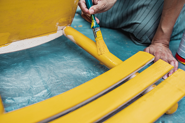 woman painting a chair with yellow paint - Structure and Behavior of Wetting Agents