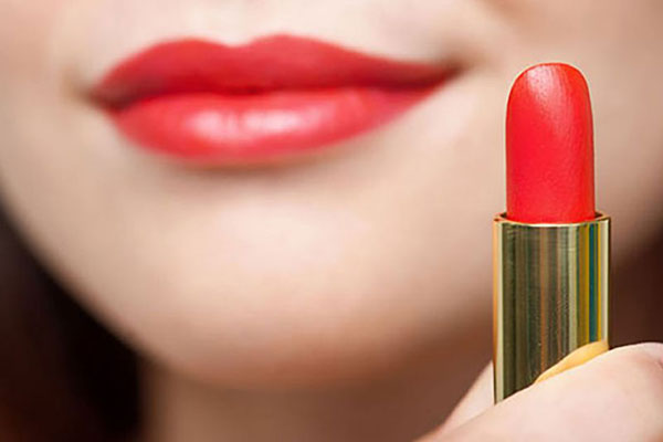 Model wearing and holding red lipstick